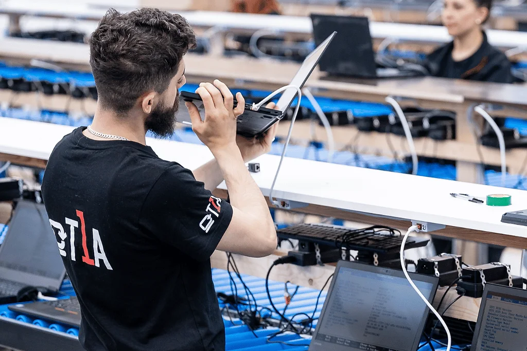 Un opérateur à son poste de travail, des portables ouverts à ses côtés, l'un affichant un écran de diagnostic