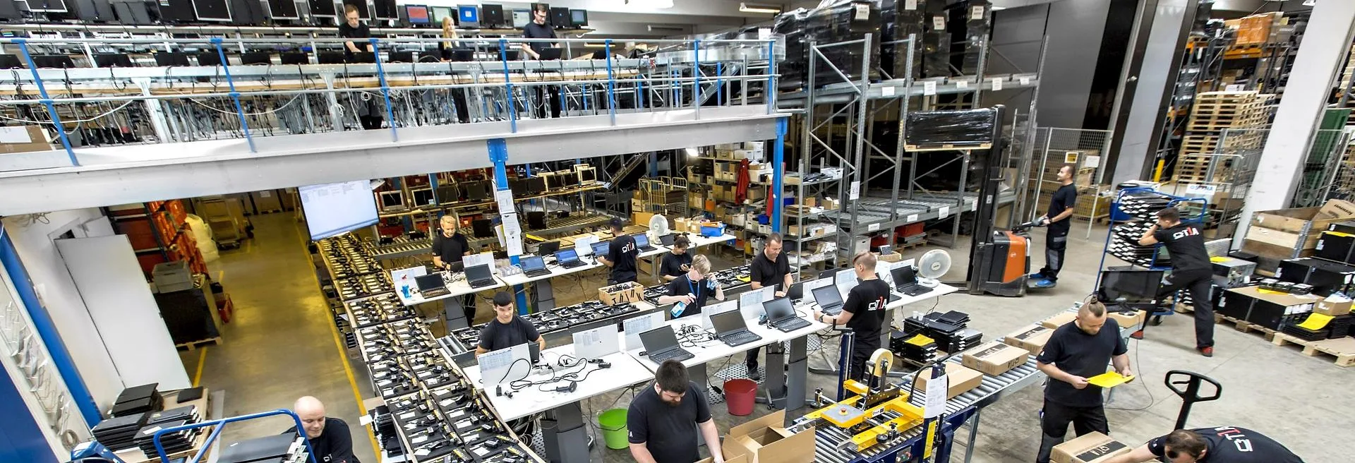 A refurbishment hall on two levels, with benches, staged hardware and a packing line