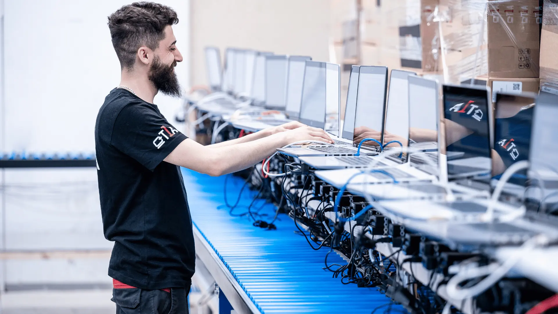 An operator working a row of notebooks connected along a blue conveyor line